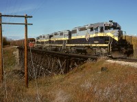 After the arduous climb from Peace River to Judah, now four miles behind them, the returning half of a GSL Turn on Northern Alberta Railways’ Peace River sub. is on essentially level prairie and crossing a minor tributary of the Heart River at mileage 37.7 near the hamlet of Marie Reine on Sunday 1980-09-28, less than four months before becoming part of Canadian National Railway.  Note the block of Pine Point ore cars behind SD38-2s 402, 403 and 404, a major traffic source from CN’s Great Slave Lake line at Roma Jct.