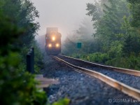 Out of the fog, CN 121 rounds the bend on the straight stretch to Berry Mills, New Brunswick. 