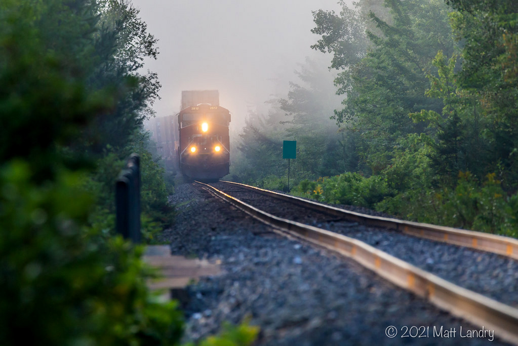 Out of the fog, CN 121 rounds the bend on the straight stretch to Berry Mills, New Brunswick.