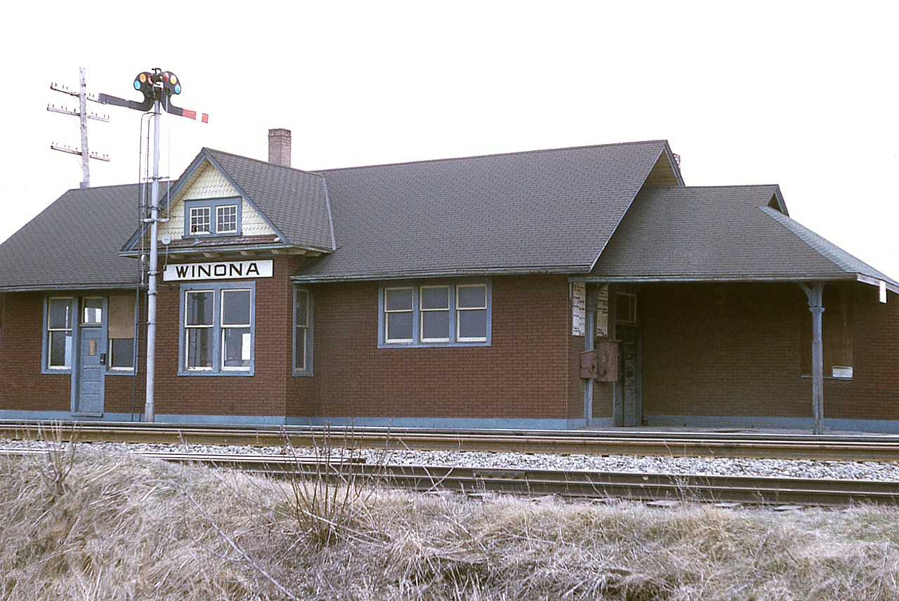 It was a real shame I could not back up any more; choice was fall down the embankment or move to the right and get a bunch of shrubs in the photo.
But you get the idea.  Winona's CN station looked pretty good going into the winter of 1974/75.  However, it did not last to see another. The structure was totally destroyed in a fire around October 1975. A real shame. 
Never heard whether there was a problem within the building or it was arson.  This station was located just off of Winona Rd opposite Railway St., a very short lane in which one could access a siding and a small yard there.
Today, the Costco and its gas bar are opposite where this rather nice building once stood.