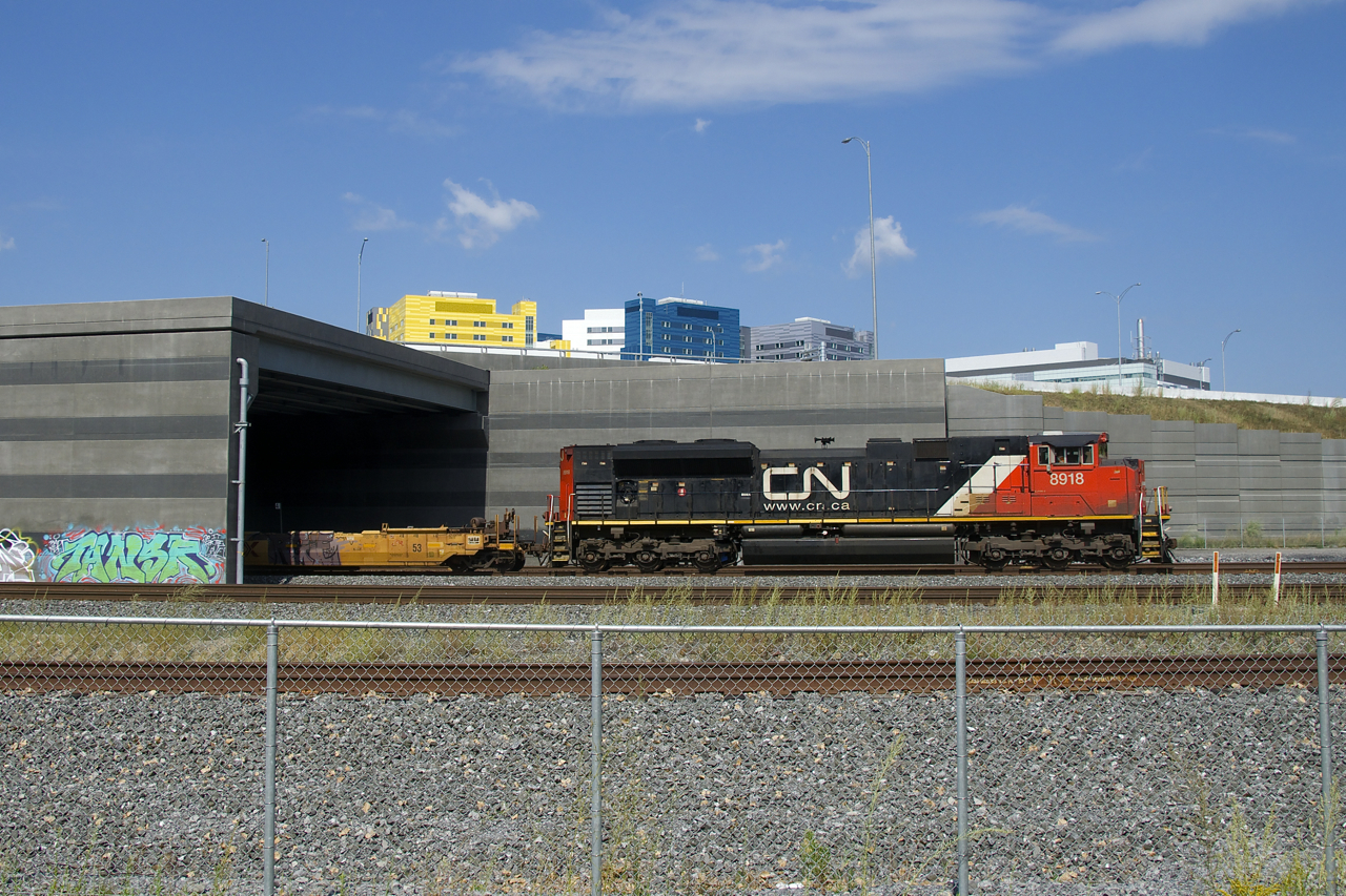 CN 599 with CN 8918 and baretables for the Port of Montreal slowly emerges from the Turcot Interchange. In a short distance it will stop and have to wait for numerous train to pass before it can continue towards the port.