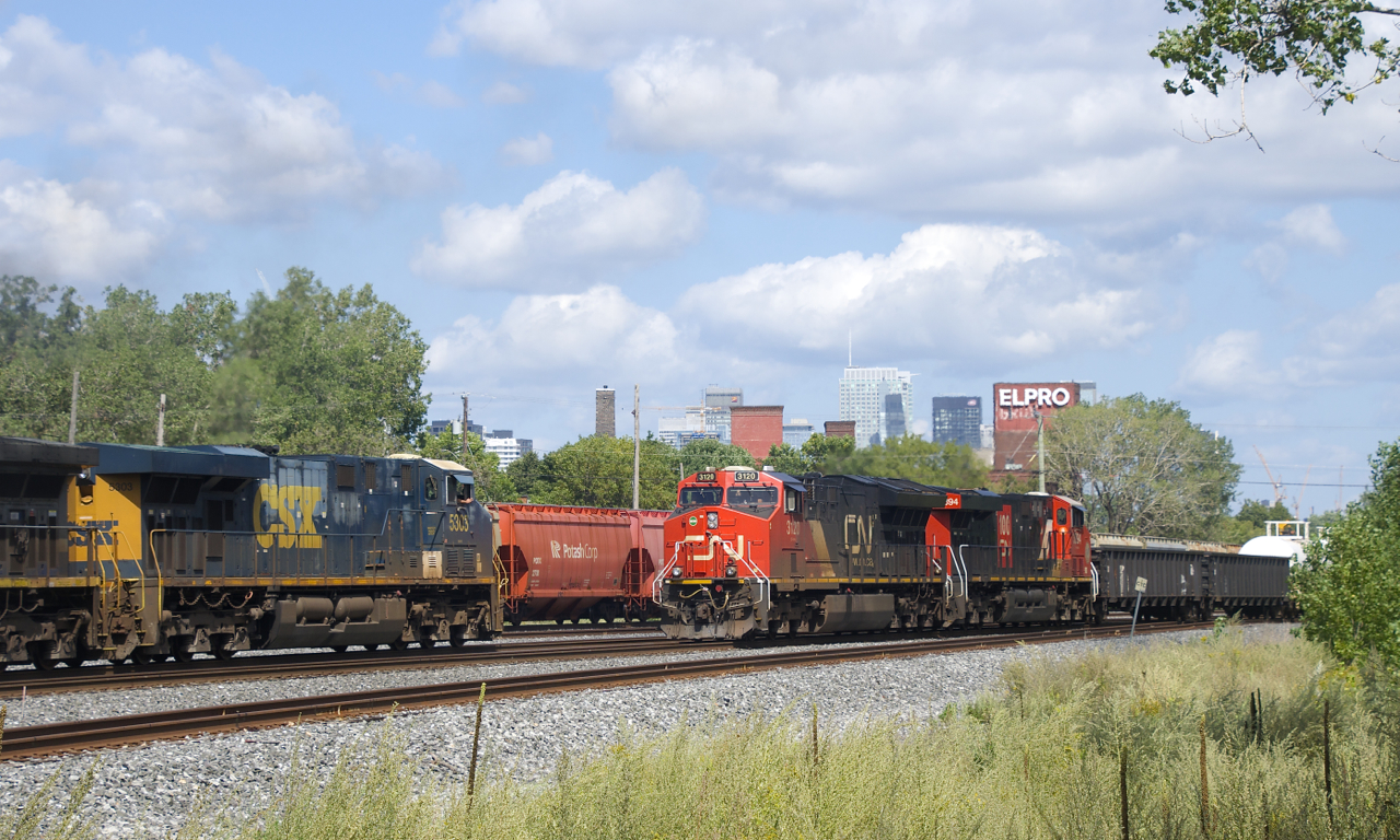 CN 599 has CSX power and a long string of baretables for the Port of Montreal as it passes CN 321. CN 599 had been waiting for its signal, but is slowly picking up speed here as the engineer waves at the passing train.