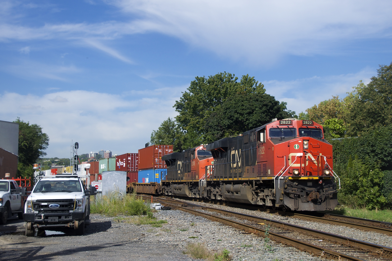 CN 120 passes some foremen as it prepares to cross the St-Ambroise Street level crossing.