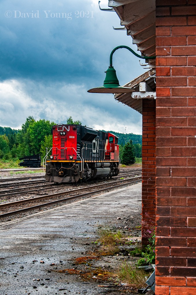 A desolate and eerie calm hangs over what was once a steady divisional point at Hawk Junction. The station seems all but abandoned. The unkept station platform has weeds and moss growing along the building where baggage carts once waited to aid in loading and unloading at train time, rocks and glass litter the rest. The only tenants now are the yellow jackets nesting underneath one of the green light fixtures. Isolated showers pass through the area. The mood is solemn. Barely even a chirp from main reservoir from the parked locomotive out front. These late summer days in 2021 see little action. No thru freights run anymore between Hearst and Sault Ste. Marie and the "Tour of the Line" passenger is six years removed from operating. Still being the home terminal for the few remaining former ACR employees, the crew will go on duty in the evening Tuesdays and Thursdays at Hawk, running light up to Oba to lift their traffic for Hearst and perhaps have cars destined for log loading, returning Wednesday and Fridays ex Hearst. They setoff their traffic in the yard at Oba before returning to Hawk Junction- again, usually light power. Although the sale of the line has been agreed upon, pending regulatory approval, these waning days of CN's ownership look bleak.
