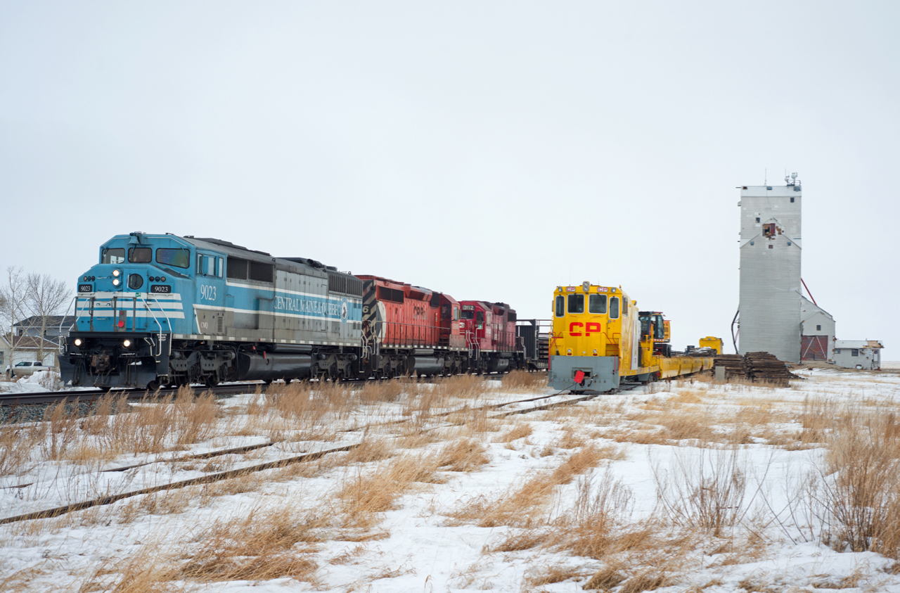 Dark and dreary weather and interesting trains go hand in hand. Such is the case in this scene as a westbound CWR train makes it's way west on the Indian Head Subdivision with CMQ 9023 up front. To the right, beyond that yellow engineering department contraption is the Pense grain elevator that was damaged by severe winds in a winter storm earlier in the year. It was torn down on May 3 2021.