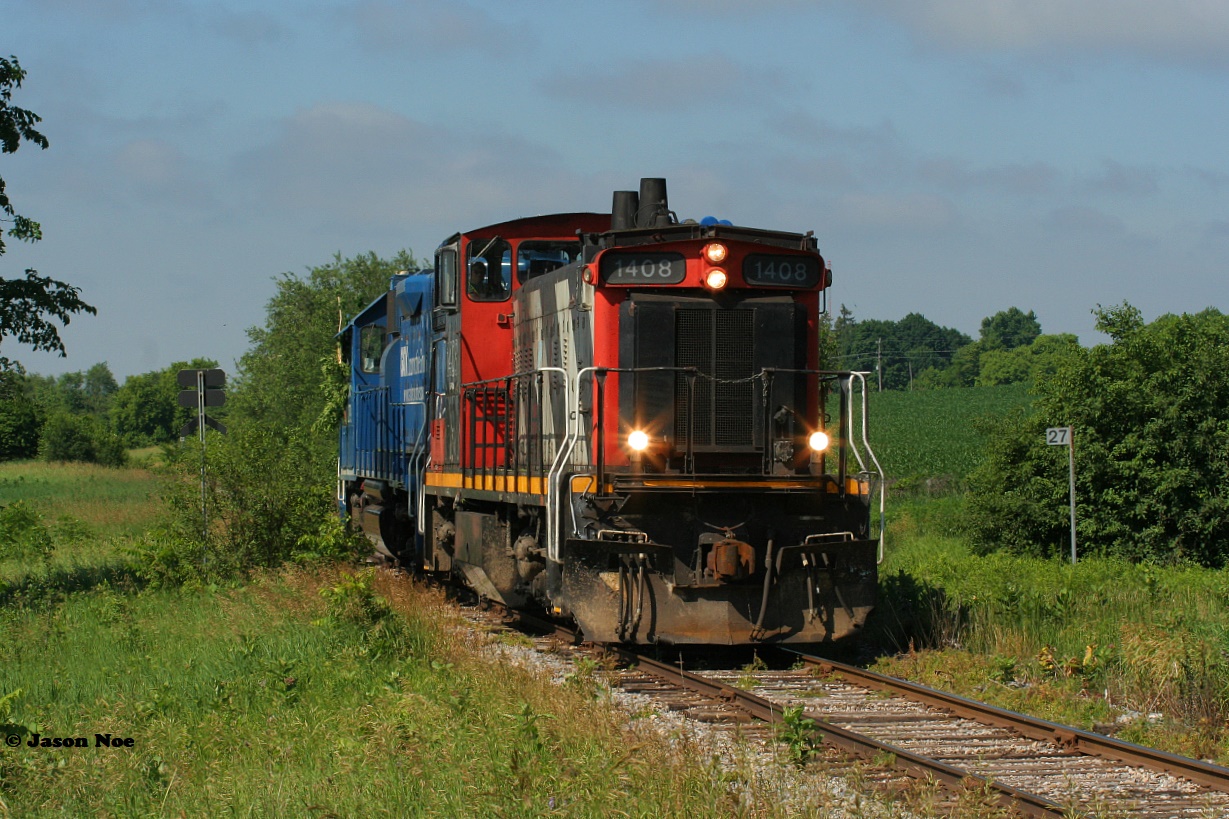 Amongst the summer growth and green foliage CN L542 slowly passes Mile 27 on the Fergus Spur. CN 1408 and GMTX 2279 were returning to Guelph light-power after setting-off loaded bulkhead cars at Hunts Logistics near Eagle Street as well as Gillies Lumber at Industrial Road in Cambridge.