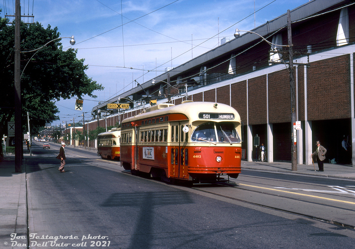 TTC PCC 4482 has just passed another PCC as it heads west on Queen Street East past the intersection for Kingston Road, operating on a Rt.501 Queen run enroute to Humber Loop.  In the background is the famed Greenwood Raceway, Toronto's east end horse racing track that opened in 1874 as the "Woodbine Race Course" that stretched along the south side of Queen Street from Greenwood Avenue to Woodbine Avenue. A new track opened in suburban Etobicoke in 1956 as the "New Woodbine Racetrack", until the "new" was dropped in 1963, and the old Woodbine site here renamed "Greenwood Raceway" after extensive renovations. It was eventually closed in 1993, demolished, and the site redeveloped into residential housing and commercial developments.  Joe Testagrose photo, Dan Dell'Unto collection slide.