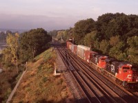 This location for most needs no explanation. By the date of this photo the entire junction had been rebuilt along with most of the Oakville subdivision. 
The morning time is the best time for the sun angle here, and this day the cloud cover was finally moving on as CN train 396 is seen coming off the Dundas sub. under early morning light, with a pair of CN's original SD70M's. If the story I heard is right they were tacked onto the end of a Norfolk Southern order from GMD and were basically built to NS specs, which explains the high headlight and lack of an isolated cab. I heard CN wasn't fond of the non-isolated cabs as they were very noisy and all future orders came with isolated cabs and low headlights as well as DPU equipment. The original order gradually had DPU installed after delivery. The greenery at Bayview has been gradually filling in, so I'm glad I spent some time here in the early years.  