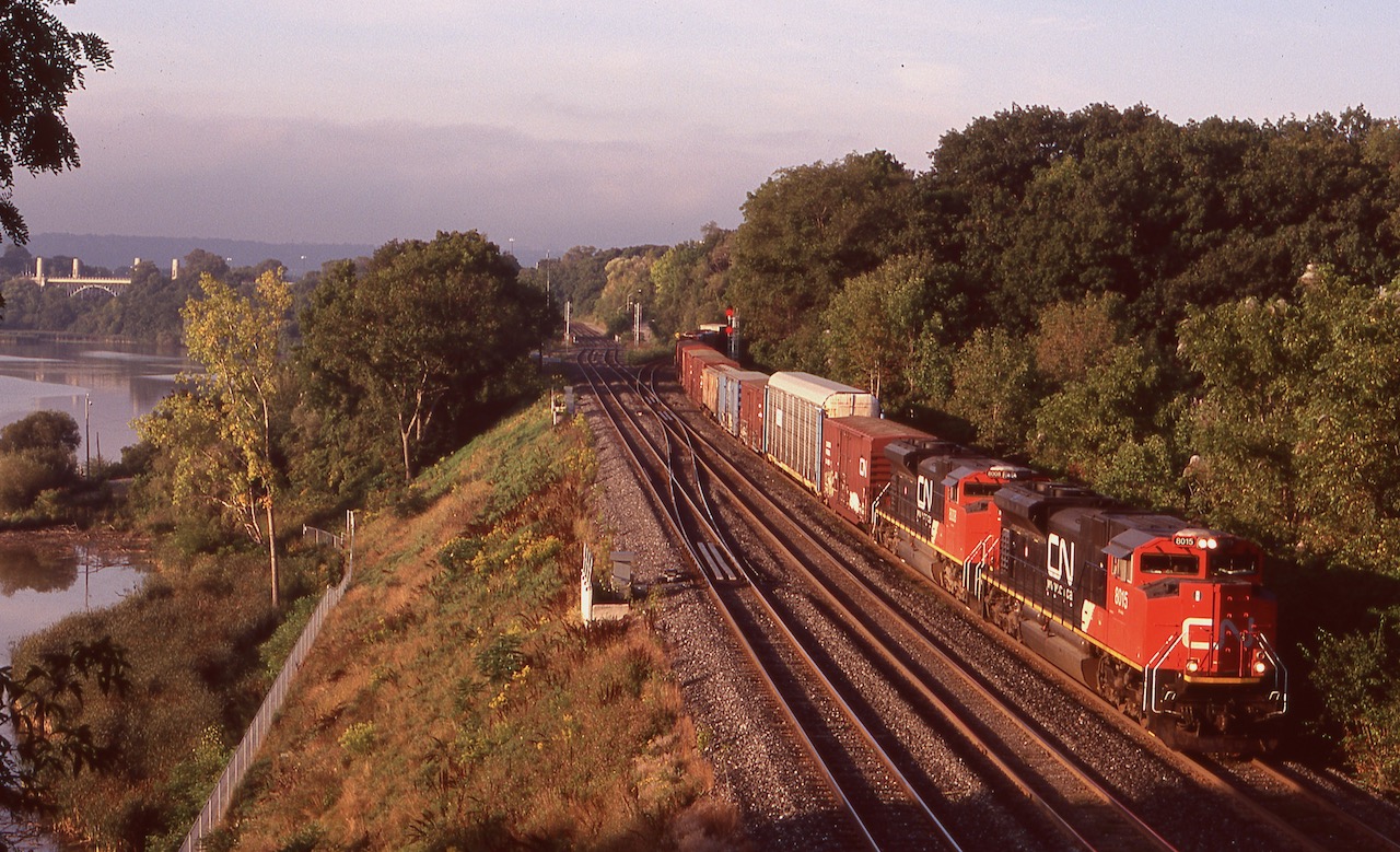 This location for most needs no explanation. By the date of this photo the entire junction had been rebuilt along with most of the Oakville subdivision. 
The morning time is the best time for the sun angle here, and this day the cloud cover was finally moving on as CN train 396 is seen coming off the Dundas sub. under early morning light, with a pair of CN's original SD70M's. If the story I heard is right they were tacked onto the end of a Norfolk Southern order from GMD and were basically built to NS specs, which explains the high headlight and lack of an isolated cab. I heard CN wasn't fond of the non-isolated cabs as they were very noisy and all future orders came with isolated cabs and low headlights as well as DPU equipment. The original order gradually had DPU installed after delivery. The greenery at Bayview has been gradually filling in, so I'm glad I spent some time here in the early years.