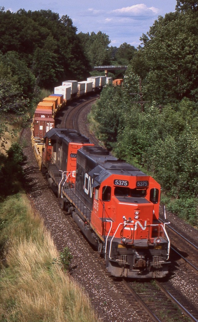 During the 1990's CN was at a point where it needed to figure out what to do with its old straight SD40 fleet, either rebuild or retire. In the end a group of 29 units were rebuilt and classified as SD40U's. As for the rest they were gradually retired and most found an extended career elsewhere, many leased back to CN as part of Alstom's GCFX lease fleet. CN decided at the time it was more cost affective to look at the secondhand market for the rest of its SD40 needs, and purchased a group of former UP/MP SD40-2's to fill the void. This day CN SD40-2 5375, ex CN 6096, exx UP 4096, exxx MP 3096, nee Mo-Pac 796 is assisted by one of CN's SD40U's as they lead intermodal train 149 or 143 westward at Bayview.