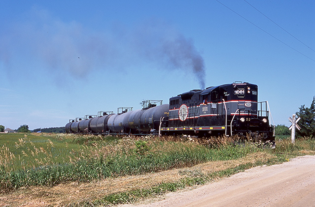 It was a somber day, but originally one that was meant to be a day at Wasaga beach with the family. I had been watching social media for a number of weeks prior anticipating the last Barrie - Collingwood train to Collingwood, but it had been some time since they last served Collingwood. This morning a last minute email changed my plans and sent me on a day long chase of the last ever train to and from Collingwood. Unfortunately it took a while to find the westbound trip so I only caught up with them east of Collingwood, but it was just light power anyway. After picking up Collingwood's mayor the train headed to the last two active customers to lift the last tank cars to ever make a trip over the line. A small celebration at the end of the spur to the last customer marked the special occasion before the slow trip back to the CP interchange at Utopia began. The train made a few stops along the way to take some photos, including stopping at this farmers field outside of Sunnidale before continuing east. Today most of the rails are still in place but are heavily grown over, with many closings paved over or filled in.