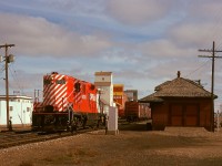 In Taber, Alberta, 2/3 of the way between Medicine Hat and Lethbridge, the hotel in the distance in this shot survives, as the Palace Hotel at the corner of 47 Ave. and 53 St., and the CP main track remains, but the locomotive and depot and distant elevators have all gone off into history.  Here, on Monday 1974-09-30, the daily westward wayfreight No. 83 with GP9 8700 has paused at the depot for switching instructions.