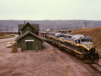 Fifty-nine years separate the origins of the depot and the SD38-2 locomotives in this shot, 1916 for the building and 1975 for the units.  NAR 403+404+402 are southbound on the second half of a GSL Turn on Thursday 1979-09-27 with concentrate loads from Pine Point Mines at the far end of CN’s Great Slave Lake line which connects to the NAR at Roma Jct. about ten miles behind the train.  The three units, typical for a GSL Turn will soon be wide open climbing to Judah, another seven miles, to reach level prairie again.