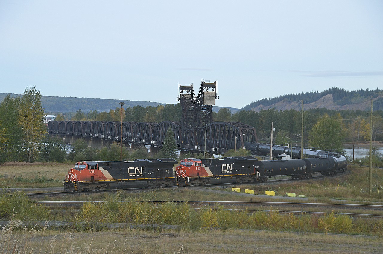 A CN oil train, led by 3051 and 3130 is seen heading southbound, crossing the "mighty" Fraser river. We stopped at the modernistic VIA station in Prince George, and the VIA "Skeena" (Prince George to Prince Rupert) was still sitting west of the station and the waiting room was full of passengers. The train should have left 35 minutes earlier, but CN once again annoyed the passenger service by leaving this oil train, blocking the Skeena.  We knew the CN would be pulling out soon, so went looking for a good vantage point for a photo and came up with this location on the east side of the river. The train is seen heading south to Vancouver after coming off the bridge. The line in the foreground is part of the way that connects to the line going off to the right, which heads to Edmonton.  Quite the bridge !!