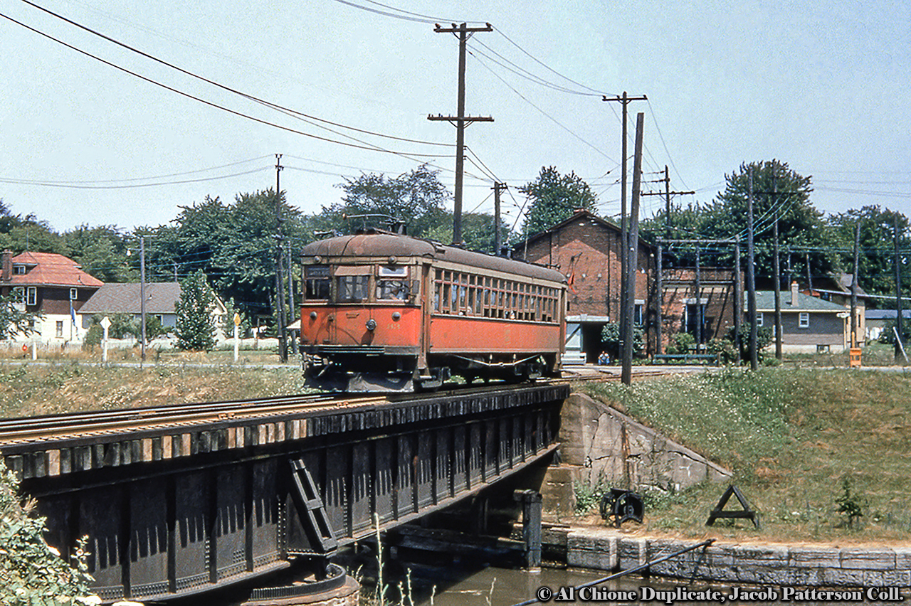 Welland-bound NS&T car 83 has just crossed Ormond Street and is seen trundling over the first/second Welland Canal on the old swing bridge.  Substation Junction is the point where the Welland Sub, running from the jct to Port Colborne, branched off from the Falls Sub (St. Catharines - Niagara Falls).  With no date provided, it is estimated this shot was taken during summer 1955, as 83 would be repainted to CNR green by March 1956.This Arnold Mooney shot from 1999 shows the same location from Ormond Street.  Where's the canal  Filled in.  The line, at that time the CN Fonthill spur, was cut short at it's namesake town and by 2000 would be operated by Trillium Railway.  Reportedly the line last saw service about 2019, and the rails lifted early 2021, removing the last piece of all the activity that once was.Original Photographer Unknown, Al Chione Duplicate, Jacob Patterson Collection Slide.