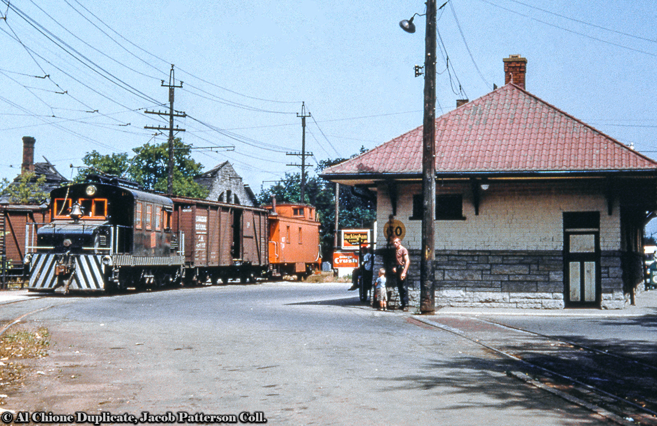NS&T motor 16 is seen passing the Thorold station with a short train.  The pocket track at right was used by interurban cars starting or ending their run keeping clear of the main for other movements to pass.  Note the burnt out structure behind the train, the remains of the James Davy Pulp Mill.  Built as a flour mill, it was purchased by Davy and his associates in 1886 and converted to a pulp and paper mill, receiving rail service from the NS&T, note the boxcar spotted off to the left.  A fire in the mid '50s destroyed much of the structure.Motor 16 was built by National Steel Car in 1918 for the Hydro Electric Power Commission. It came to the NS&T in 1922 and was rebuilt in 1930. In September 1960 it was transferred to the Oshawa Railway (also under CN Electric Railways) as their 16.  In November 1964 it was sold to Noranda Mines as their 20.  Further disposition unknown.Original Photographer Unknown, Al Chione Duplicate, Jacob Patterson Collection slide.
