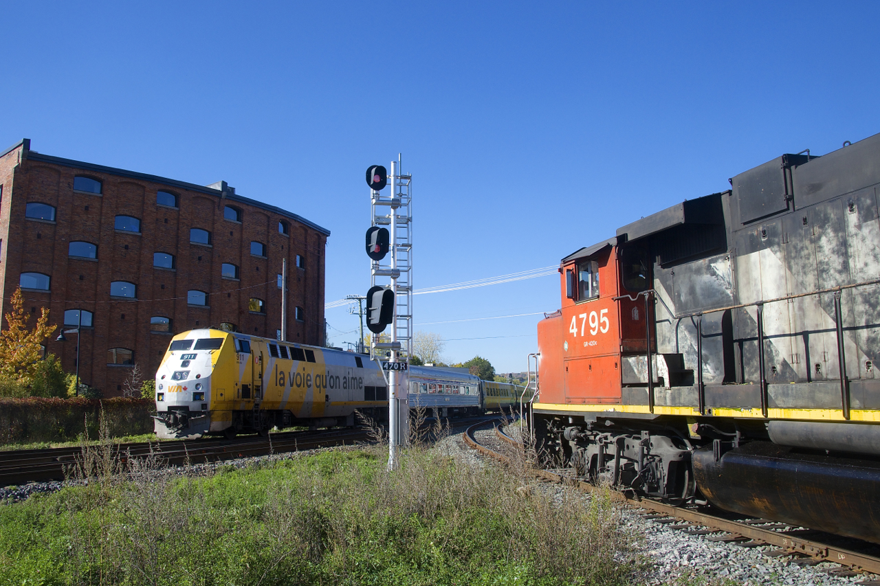 VIA 24 with VIA 911 and a HEP/LRC consist is passing CN 4795 on the CN East Side Canal Bank Spur. The Pointe St-Charles is about to accept a Slow to Stop signal and temporarily enter the main line for headroom, before backing on to the Spur.