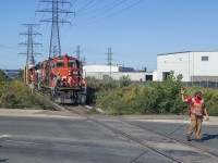 The conductor on the 0700 job has the crossing protected and waves his partner, who is controlling the movement, to come ahead.  Once clear of the road they will spot the box at Parkdale Warehousing before proceeding <a href=http://www.railpictures.ca/?attachment_id=46525>over to Railcare.</a>