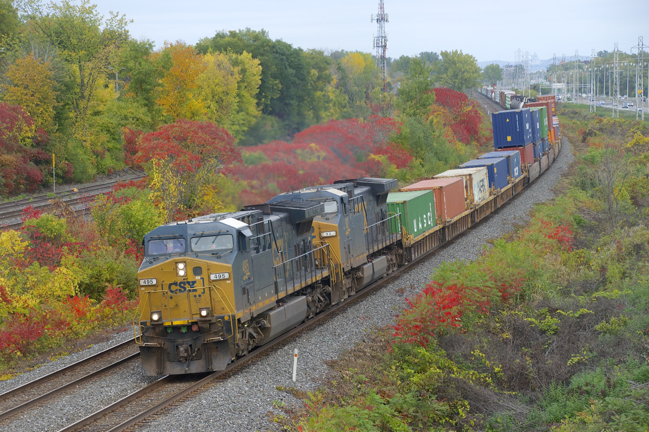 A pair of repainted CSXT AC4400CW's (CSXT 495 & CSXT 92) lead a long CN 327 (122 cars) around a curve in Beaconsfield, with fall colours nearly at their peak
