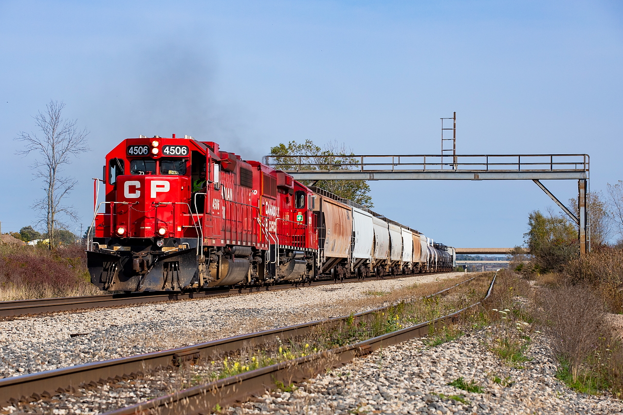 On a hot and hazy Thanksgiving Monday, CP 4506 and CP 2270 are giving it all they have as CP TE11 summits the grade out of the Welland Canal tunnel cut with 17 cars lifted from CN Southern Yard. The cars are for Innophos in Port Maitland (hoppers and white/black tanks) and Chemtrade (black tanks) in Niagara Falls. The track in the foreground is CP's Rusholme Siding, which currently (and often) has racks stored on it. It is also used by both CP and CN to access Trillium's Cayuga Spur for interchange.