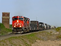 An eastbound mixed freight passes a derelict elevator on the CN main east of Edmonton
