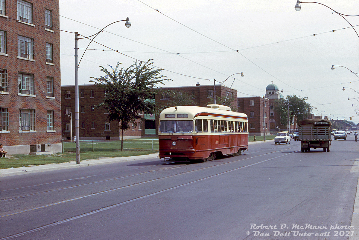 TTC 4269 (an air-electric A4-class PCC built in 1944) heads westbound on Dundas Street East on the lengthy Harbord route (bound for Lansdowne Loop) passing by apartment buildings of the famed Regent Park neighbourhood, at Regent Street east of Parliament Street. Visible in the background is part of the Sts Cyril & Methody Macedonian-Bulgarian Eastern Orthodox Church at Dundas & Sackville, built in 1948 and still present today. I've never seen too many transit photos taken along this stretch, likely because this wasn't the most picturesque part of the city by any stretch, and in later years Regent Park gained a less-than stellar reputation.Regent Park was a post-war affordable housing project by the government, Canada's largest public housing project at the time. A run-down area to the east of downtown Toronto off Parliament Street (historically considered a slum home to the poor, working class and new immigrants) was razed for new affordable housing apartment complexes and public housing starting in the late 40's, with redevelopment continuing until 1960. Matters seemed to get worse over time, with crime, gangs, poverty, poor living conditions and social problems in the area continuing or taking hold over the decades. Criticisms of the original plan include having much of the area as residential housing only (instead of mixed work-residential-commercial use), much of the design being utilitarian and bland with no frills (not a very aesthetic place to live or visit), and urban planning policies at the time proving to be detrimental (replacing many of the former public streets with sidewalk networks in the new development, creating an inward-focused environment).Eventually plans for public-private redevelopment and gentrification of Regent Park, including demolishing and replacing the aging apartment buildings, were introduced in the 2000's. Included were plans for a certain amount of affordable housing, i.e. having a mixed social-economic demographic of residents (although some argue it unintentionally forces long-time lower-income residents out through local gentrification and increased property values, but that's another story).As with most of the TTC's older air-electric PCC's, 4269 was stored following the opening of the new Bloor-Danforth subway line in February 1966, which rendered part of the (older) streetcar fleet surplus. Its disposition is unknown, but photos show it did end up in the Hillcrest PCC deadline, so was likely cut up for scrap there in the late 60's with some other unsold cars. Some luckier sister cars were noted as being sold to Alexandria, Egypt.Robert McMann photo, Dan Dell'Unto collection slide.