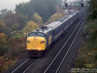 VIA FP7 6569 cuts through the afternoon fall gloom, piloting Windsor-Toronto train #72 eastbound through Bayview Junction with five of the blue & yellow fleet in tow. Late in its VIA career and approaching the 1990 service reductions, 6569 was one of the few ex-CP locomotives still on the VIA roster at this time.
<br><br>
What follows is the story of ol' VIA 6559: she was originally built by GMD London in 1952 as Canadian Pacific 4069, a dual freight/passenger service FP7 unit. A renumbering followed two short years later when it became 1425 for service on CP's new transcontinental passenger train "The Canadian" in 1954. The 1400-series units were CP's numbering range for high-speed passenger F-units equipped with 89mph gearing, as opposed to the normal 65mph gearing in 4000-series F's. It was renumbered back to 4069 and regeared back to 65mph in 1965 due to a decreasing need for strictly passenger units, but still saw passenger use out east on <a href=http://www.railpictures.ca/?attachment_id=42540><b>The Canadian (Toronto-Sudbury)</b></a>, and the Atlantic Ltd and commuter trains out of Montreal (as well as in normal freight service).
<br><br>
When VIA took over CP's passenger services in September 1978, CP sold them a handful of their worn-out fleet of passenger units including 4069 (reportedly for $7,000 each, with the stipulation CP had right of first refusal when VIA disposed of them). According to notes from former CP motive power guru Bruce Chapman, after years of transcontinental passenger service, some of the 1400-series units were in the 4-million mile range and climbing to 5. The few CP 4000's sold to VIA received their old 1400-series numbers, so 4069 once again became "CP" 1425 under VIA (not repainted in VIA colours under that number). The entire lot were planned to be rebuilt and upgraded to VIA/CN standards at CN's Point St. Charles shop and renumbered into the 6550- and 6650- series. 1425 was one of the few lucky ex-CP units to be rebuilt, emerging as VIA 6569 in 1980.
<br><br>
When the early 80's VIA service cuts came about, the rebuild program ended with only a small handful of units done, and most of the unrebuilt ex-CP F's (some still painted CP) were sold back to CP in 1983 (reportedly for $7,000 + $1). CP wanted them to use their engine blocks and other components in the GP7/GP9 rebuild pool, and most of the gutted carbodies sat around for possible reuse until they were scrapped around 1987. The few rebuilt VIA 6550/6650-series units, including 6569, continued to serve VIA until being disposed of around the early 90's. The West Coast Railway Association acquired VIA 6569 in 1994, and in 1999 it underwent restoration back to CP maroon and grey paint, and was renumbered once again to original number 4069.
<br><br>
<i>Bill McArthur photo, Dan Dell'Unto collection slide.</i>