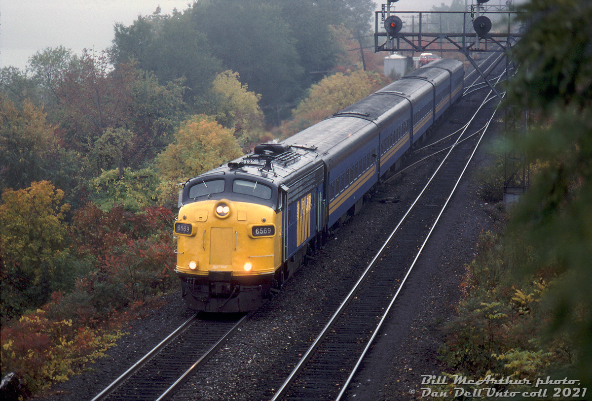 VIA FP7 6569 cuts through the afternoon fall gloom, piloting Windsor-Toronto train #72 eastbound through Bayview Junction with five of the blue & yellow fleet in tow. Late in its VIA career and approaching the 1990 service reductions, 6569 was one of the few ex-CP locomotives still on the VIA roster at this time.

What follows is the story of ol' VIA 6559: she was originally built by GMD London in 1952 as Canadian Pacific 4069, a dual freight/passenger service FP7 unit. A renumbering followed two short years later when it became 1425 for service on CP's new transcontinental passenger train "The Canadian" in 1954. The 1400-series units were CP's numbering range for high-speed passenger F-units equipped with 89mph gearing, as opposed to the normal 65mph gearing in 4000-series F's. It was renumbered back to 4069 and regeared back to 65mph in 1965 due to a decreasing need for strictly passenger units, but still saw passenger use out east on The Canadian (Toronto-Sudbury), and the Atlantic Ltd and commuter trains out of Montreal (as well as in normal freight service).

When VIA took over CP's passenger services in September 1978, CP sold them a handful of their worn-out fleet of passenger units including 4069 (reportedly for $7,000 each, with the stipulation CP had right of first refusal when VIA disposed of them). According to notes from former CP motive power guru Bruce Chapman, after years of transcontinental passenger service, some of the 1400-series units were in the 4-million mile range and climbing to 5. The few CP 4000's sold to VIA received their old 1400-series numbers, so 4069 once again became "CP" 1425 under VIA (not repainted in VIA colours under that number). The entire lot were planned to be rebuilt and upgraded to VIA/CN standards at CN's Point St. Charles shop and renumbered into the 6550- and 6650- series. 1425 was one of the few lucky ex-CP units to be rebuilt, emerging as VIA 6569 in 1980.

When the early 80's VIA service cuts came about, the rebuild program ended with only a small handful of units done, and most of the unrebuilt ex-CP F's (some still painted CP) were sold back to CP in 1983 (reportedly for $7,000 + $1). CP wanted them to use their engine blocks and other components in the GP7/GP9 rebuild pool, and most of the gutted carbodies sat around for possible reuse until they were scrapped around 1987. The few rebuilt VIA 6550/6650-series units, including 6569, continued to serve VIA until being disposed of around the early 90's. The West Coast Railway Association acquired VIA 6569 in 1994, and in 1999 it underwent restoration back to CP maroon and grey paint, and was renumbered once again to original number 4069.

Bill McArthur photo, Dan Dell'Unto collection slide.