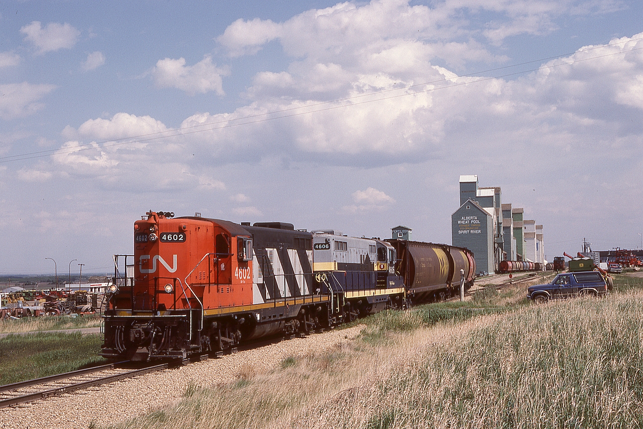 After the 1981-01-01 takeover by CN of Northern Alberta Railways, NAR power was renumbered into the CN series, then later the Northern Alberta lettering and diamond symbols were blacked out, and eventually (typically coinciding with overhauls) full CN paint was applied.  One full and one partial remarking are shown here, 4602 the former NAR 201 and 4606 formerly NAR 205.  Spirit River is at the very west end of the CN Smoky subdivision, five miles west of a junction at Rycroft where most traffic runs south to Grande Prairie, and the five-mile stretch is utilized now for car storage.  The crossing in the photo is 52 Street, and the grain elevators and trackage seen here are now history for five blocks east, all blank to 47 Street.