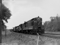 Canadian National 2209, one of CN's handfull of CLC H16-44 units, leads a GP9 on a northbound freight on the Bala Sub rolling through Sparrow Lake in Ontario's "Cottage Country" during July 1962. Sparrow Lake proper was located at mile 93.9 of CN's Bala Sub (north of Washago, near the southwest point of its namesake lake), although this photo was likely taken to the south at the crossing by Port Stanton Parkway and South Port Sparrow Lake Road.
<br><br>
During the early rush to dieselization, the Canadian Locomotive Company of Kingston, Ontario was licensed to manufacture and sell Fairbanks-Morse locomotive designs in Canada. CN and CP were their main Canadian customers, taking multiple orders in the 1950's to build up their new diesel fleets and banish steam. CN purchased 4- and 5-axle C-Liners, H16-44's, a lone H24-66 "Train Master" unit, and some smaller offerings including H10-44, H12-44 and oddball H12-64 models. They differentiated from the competition by using Fairbanks-Morse's opposed-piston diesel engines, a well-regarded design popular in marine use.
<br><br>
2209 was one of 18 H16-44 units CN purchased from CLC in 1955, first numbered 1841-1858 and later renumbered 2200-2217. Unlike most of CP's fleet of FM-CLC units that were based out of the west, CN's C-Liners and H16-44's were based in the east, and ran mixed with other equivalent models from competitor GMD and MLW pulling mainline freight and passenger trains in Ontario, Quebec, Eastern Canada and (early on) Vermont. CN's H16-44 units were also set up to run long hood forward, like most of their hood units at the time.
<br><br>
As the 1960's rolled around, FM-CLC had exited the locomotive market, and oddball first generation locomotives fell out of favour on most Canadian and US railroads. Most mainline FM-CLC units ended up retired and traded in or scrapped during this period (some were bought by marine supply outfits for their opposed-piston engines). CN's FM-CLC fleet was retired during the mid-late 1960's, and many of the stripped carbodies ended up in the scrap lines at <a href=http://www.railpictures.ca/?attachment_id=35674><b>London</b></a> and Montreal awaiting the final indignity from the torch. CP's lasted a few years more until the bulk of their fleet were retired during <a href=http://www.railpictures.ca/?attachment_id=42299><b>1975</b></a>.
<br><br>
<i>Original photographer unknown, Dan Dell'Unto collection negative (large-format scanned with a DSLR).</i>