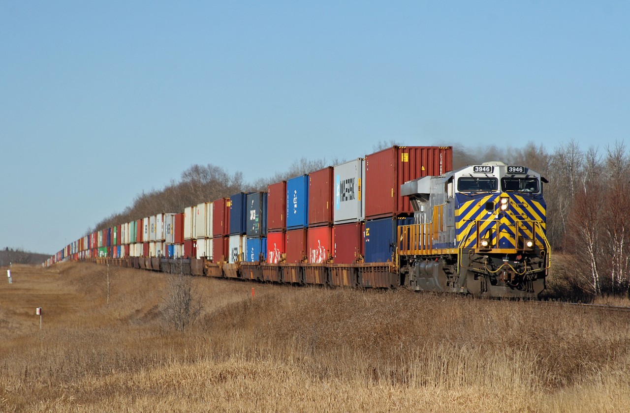 Q 19651 27 rolls through Deville, Alberta with CN 3946 on the point.