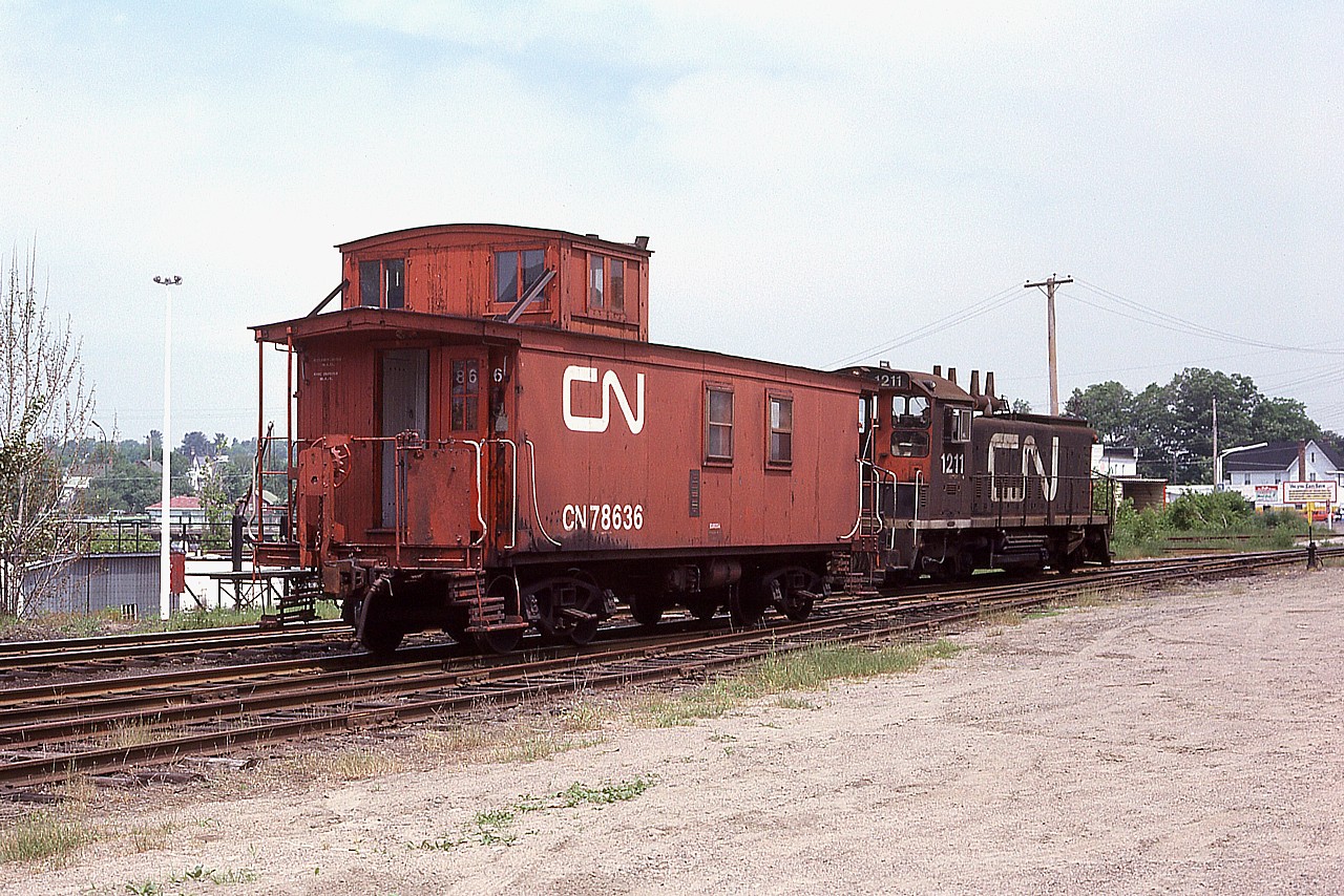 A number of years ago Parry Sound industry was served by a CN local that was stationed along Great Northern Road just the other side of the CP trestle from the large oil tank facilities. When the oil business was gone, so was the CN. The small yard and the equipment you see here have long since departed. This location is right in front of the present day Trestle Brewery and Restaurant in town, south side of the Seguin River between main artery Bowes St and the CP trestle.  CN 1211 was retired in 1993 and the old wooden caboose 78636, built back in the 1912-1920 era; I understand is still in existence. Privately owned and minus its trucks, in Palmerston, ON. Can anyone verify this?