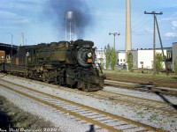 Canadian National 3419 (an S1f-class 2-8-2 Mikado built by Alco for the Grand Trunk in 1913, and scrapped in 1957) heads up a fast-moving freight westbound on CN's Oakville Sub between Swansea and Mimico. The steamer has just ducked under the Queen Elizabeth Way overpass (note the old QEW curved light standards, and prominent monument in the median) and is passing by the new Christie Brown bakery at Lake Shore & Park Lawn. Spurs and sidings in the background run off the mainline along the north side of the property to serve roll-up doors into the building.<br><br>Known in CN timetables as <a href=http://www.railpictures.ca/?attachment_id=43270><b>Mimico East</b></a>, the four Oakville Sub mainline tracks here emphasize the busy rail corridor full of freights, locals, tranfers and passenger trains heading to and from Union Station, <a href=http://www.railpictures.ca/?attachment_id=32164><b>Mimico Yard</b></a>, Don Yard and Danforth Yard in an era before the decline of passenger service, and the future "Toronto Bypass" diverting much of CN's freight traffic north to MacMillan Yard. The closest track is a service track for the <a href=http://www.railpictures.ca/?attachment_id=36009><b>Ontario Food Terminal</b></a> to the east of the QEW, and the other four are mainline tracks.<br><br>The large Christie Brown (Mr. Christie's) Lakeshore Bakery plant opened in 1950 and operated for decades before closing in 2013. The whole factory was eventually demolished for redevelopment, but the water tower was spared for historical purposes. The 1940's QEW Monument was moved to a nearby public park at the mouth of the Humber River due to a highway widening project in the mid-70's.<br><br><i>Original photographer unknown, Dan Dell'Unto collection slide.</i>
