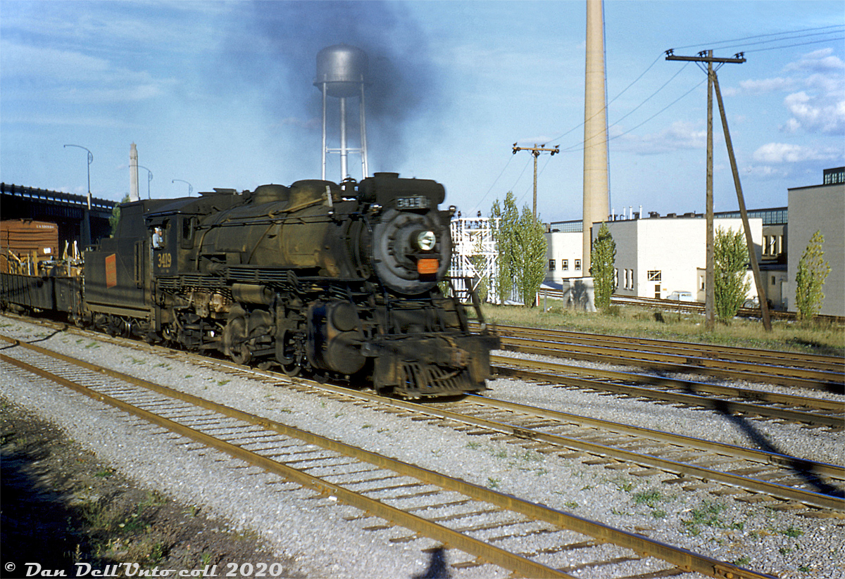 Canadian National 3419 (an S1f-class 2-8-2 Mikado built by Alco for the Grand Trunk in 1913, and scrapped in 1957) heads up a fast-moving freight westbound on CN's Oakville Sub between Swansea and Mimico. The steamer has just ducked under the Queen Elizabeth Way overpass (note the old QEW curved light standards, and prominent monument in the median) and is passing by the new Christie Brown bakery at Lake Shore & Park Lawn. Spurs and sidings in the background run off the mainline along the north side of the property to serve roll-up doors into the building.

Known in CN timetables as Mimico East, the four Oakville Sub mainline tracks here emphasize the busy rail corridor full of freights, locals, tranfers and passenger trains heading to and from Union Station, Mimico Yard, Don Yard and Danforth Yard in an era before the decline of passenger service, and the future "Toronto Bypass" diverting much of CN's freight traffic north to MacMillan Yard. The closest track is a service track for the Ontario Food Terminal to the east of the QEW, and the other four are mainline tracks.

The large Christie Brown (Mr. Christie's) Lakeshore Bakery plant opened in 1950 and operated for decades before closing in 2013. The whole factory was eventually demolished for redevelopment, but the water tower was spared for historical purposes. The 1940's QEW Monument was moved to a nearby public park at the mouth of the Humber River due to a highway widening project in the mid-70's.

Original photographer unknown, Dan Dell'Unto collection slide.