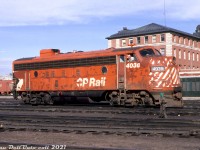 "Slap some numbers on it and get it out the door!" was probably the mantra of CP at the time, as there had been a <a href=http://www.railpictures.ca/?attachment_id=31972><b>shutdown of the Angus paint shops</b></a> and likely a backlog of units to repaint at Ogden. As a result, a bunch of units in for work including <a href=http://www.railpictures.ca/?attachment_id=35869><b>C424's</b></a>, RS18's and F-units were given some sandblasting, bodywork, touch-ups with grey or oxide red primer, had some legible numbers slapped on the cab and were sent out the shop door back into service. FP7 4038 is one such specimen, still in the old 5" stripe "Action Red" paint sporting no shortage of bodywork touch-ups and oxide red primer as she gets hostled around the yard in Moose Jaw, Saskatchewan. A fresh red Nathan Airchime M3H sits on the filthy roof with its normal coating of weathering and grime, except for the removable roof panels and winterization hatch (either repainted or cleaned off during removal/overhaul), and the radiator fans appear unpainted. Curiously, the rim around the front headlight is missing.<br><br>The end came for CP's F-unit fleet in the early 1980's, and most units were parked and later scrapped (fun fact, the first order of CP GP38-2's featured overhauled trucks taken from retired F-units). 4038 was retired in 1982, but would be spared the torch and donated for display in Minnedosa, Manitoba. <br><br> <i>Original photographer unknown, Dan Dell'Unto collection slide.</i>