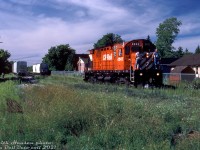 <b>Final curtain call for the Bobcaygeon Sub:</b> Overgrown yard tracks and piles of removed rails reflected the dwindling importance of many low-traffic branchlines on the CP system in the 1980's, many of whose days were numbered. CP C424 4242 works an extra freight (likely the Lindsay Turn from Toronto) switching a few hoppers at the CN-CP interchange at Lindsay, Ontario at the end of the Bobcaygeon Subdivision in the Summer of 1987. The view here is looking north from Queen Street near the former station site, east of Lindsay Street North. CN had a short spur line, the Lindsay River Spur, running up from their main Campbellford Sub branchline along the Scugog River to get to the CP interchange (once part of a larger network of CN lines in the area, by this time also dwindling). CP's MLW C424, RS18u, and GMD GP35 roadswitcher units solo and in pairs were common 4-axle branchline power in the east at the time (the RS18 rebuilt program was cutting into the ranks of its unrebuilt 8700's, and CP didn't start its 8200-series roadswitcher GP9u rebuilds en-masse until 1988).<br><br>CP's Bobcaygeon Sub, originally constructed in the early 1900's, branched off the Havelock Sub at Dranoel and ran 18 miles north to Lindsay. It once continued north all the way to its namesake town Bobcaygeon at Mile 34, but that section north of Lindsay was abandoned in 1961. There was also a CP line running north-west from Lindsay to Port McNicoll via Orillia, but a chunk was abandoned in 1937 and the remaining portion became CP's Port McNicoll Sub (abandoned in sections between 1976 and 1992).<br><br>At this time there would only be a few more months of CP service for Lindsay, as the final portion of the Bobcaygeon Sub from Dranoel to Lindsay would be abandoned in November 1987. CN would pick up any remaining CP customers in Lindsay, but three years later CN would also leave town for good (abandoning the Campbellford Sub from <a href=http://www.railpictures.ca/?attachment_id=35280><b>Peterborough</b></a> to Lindsay in June 1989, and the Uxbridge Sub north of Stouffville to Lindsay in December 1990). <br><br> Once a town full of branchlines reaching out in all directions, by the time the early 90's rolled around no train would call on Lindsay again.<br><br><i>Keith Hansen photo, Dan Dell'Unto slide collection.</i>
