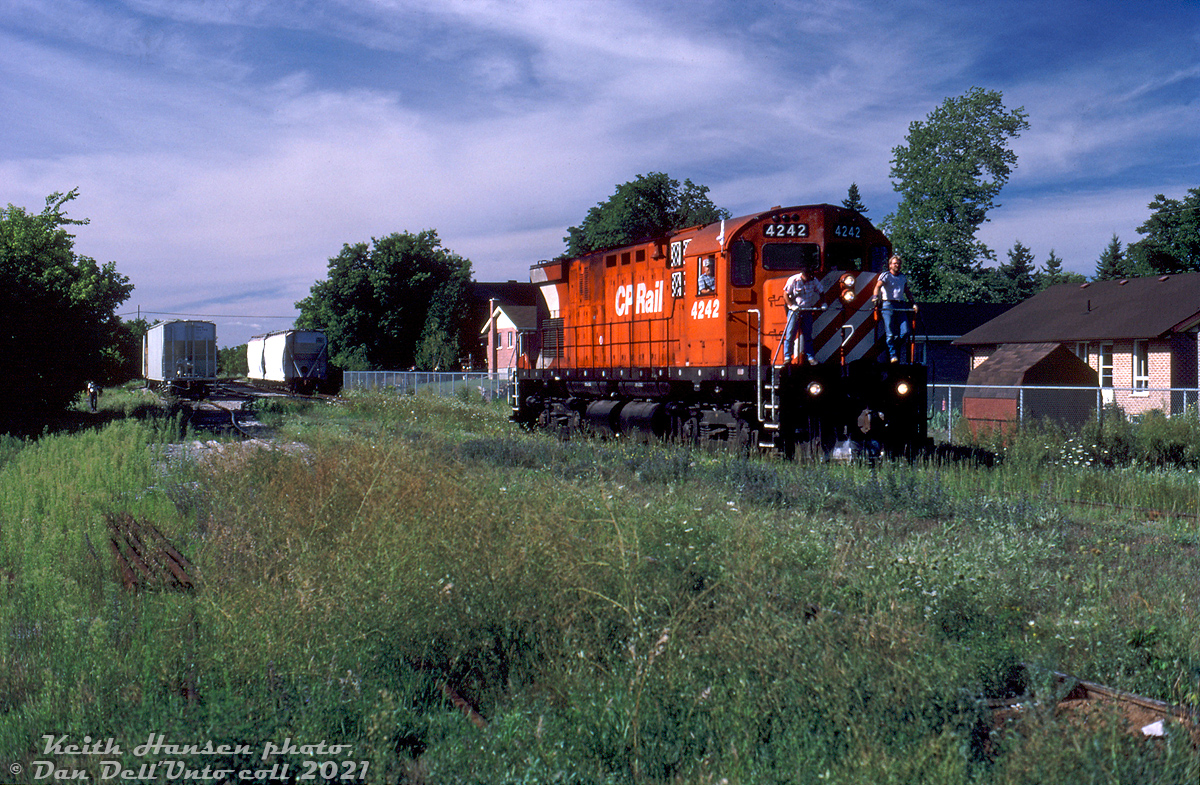 Final curtain call for the Bobcaygeon Sub: Overgrown yard tracks and piles of removed rails reflected the dwindling importance of many low-traffic branchlines on the CP system in the 1980's, many of whose days were numbered. CP C424 4242 works an extra freight (likely the Lindsay Turn from Toronto) switching a few hoppers at the CN-CP interchange at Lindsay, Ontario at the end of the Bobcaygeon Subdivision in the Summer of 1987. The view here is looking north from Queen Street near the former station site, east of Lindsay Street North. CN had a short spur line, the Lindsay River Spur, running up from their main Campbellford Sub branchline along the Scugog River to get to the CP interchange (once part of a larger network of CN lines in the area, by this time also dwindling). CP's MLW C424, RS18u, and GMD GP35 roadswitcher units solo and in pairs were common 4-axle branchline power in the east at the time (the RS18 rebuilt program was cutting into the ranks of its unrebuilt 8700's, and CP didn't start its 8200-series roadswitcher GP9u rebuilds en-masse until 1988).CP's Bobcaygeon Sub, originally constructed in the early 1900's, branched off the Havelock Sub at Dranoel and ran 18 miles north to Lindsay. It once continued north all the way to its namesake town Bobcaygeon at Mile 34, but that section north of Lindsay was abandoned in 1961. There was also a CP line running north-west from Lindsay to Port McNicoll via Orillia, but a chunk was abandoned in 1937 and the remaining portion became CP's Port McNicoll Sub (abandoned in sections between 1976 and 1992).At this time there would only be a few more months of CP service for Lindsay, as the final portion of the Bobcaygeon Sub from Draneol to Lindsay would be abandoned in November 1987. CN would pick up any remaining CP customers in Lindsay, but three years later CN would also leave town for good (abandoning the Campbellford Sub from Peterborough to Lindsay in June 1989, and the Uxbridge Sub north of Stouffville to Lindsay in December 1990).  Once a town full of branchlines reaching out in all directions, by the time the early 90's rolled around no train would call on Lindsay again.Keith Hansen photo, Dan Dell'Unto slide collection.