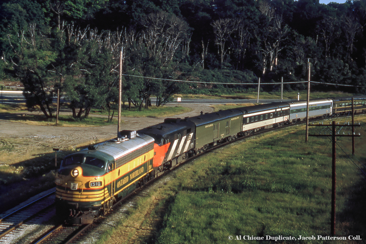 Following up on Dan's recent post, here is another shot of the ONR/CNR overnight sleeper "Northland" led by ONR FP7 1510 and CN FPA-4 6779 alongside Rosedale siding about to duck under the Don Valley Parkway on/off ramp near Bayview Avenue (in background) just north of Bloor.  As seen in the images linked below, the "North;and" often had interesting consists as it was made up of equipment from both ONR and CN, and later ONR and VIA.  Today's consist includes an ONR baggage car and two CN cars bracketing an ONR car in the fairly unique "Progressive Green" scheme.  This paint scheme dates the slide to about 1970 or slightly earlier.Ontario Northland introduced it's Progressive Green scheme in 1966, having five locomotives painted in the scheme.  These include ONR FP7s 1502 and 1517 (seen here at Allandale),  FP7 1521 (seen here at Oakville/Burlington), RS3 1311 (seen here at North Bay), and S-2 1200 (seen here at North Bay).  The FP7s were repainted in about six years, however the switchers carried the scheme until retirement.  Freight equipment carried this scheme, and it would appear some passenger equipment did as well.  The shields carried on the side of the FP7s appears twice on each side of the third car in this train.  A close up of lunch/cafe car "Meechim" in this scheme can be found here for comparison.More "Northland":1977 near Don Mills Road by Steve Danko.1978 by Queen Street by David Parker.Original Photographer Unknown, Al Chione Duplicate, Jacob Patterson Collection Slide.
