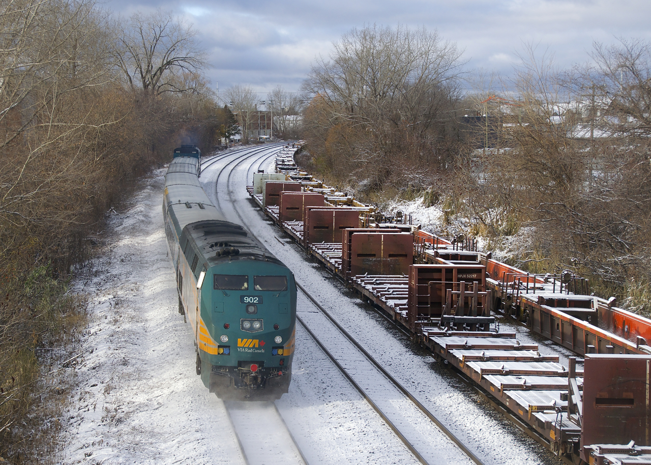VIA 63 passes aluminum cars stored on the Freight Track of CN's Montreal Sub and well cars stored on the Transfer Track.