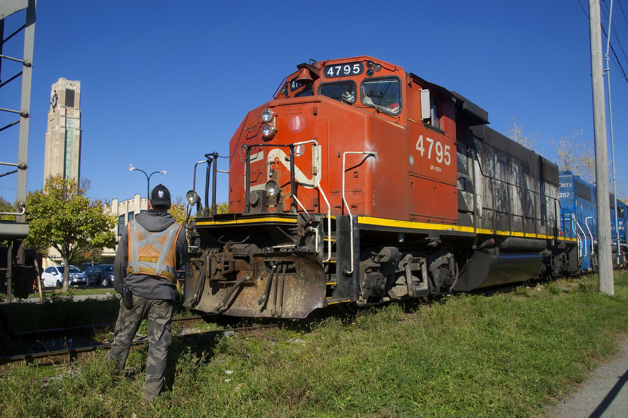 The conductor looks on as CN 4795 is about to couple onto some grain cars on the East Side Canal Bank Spur. At left is the clock tower of the Atwater Market, which opened in 1933.