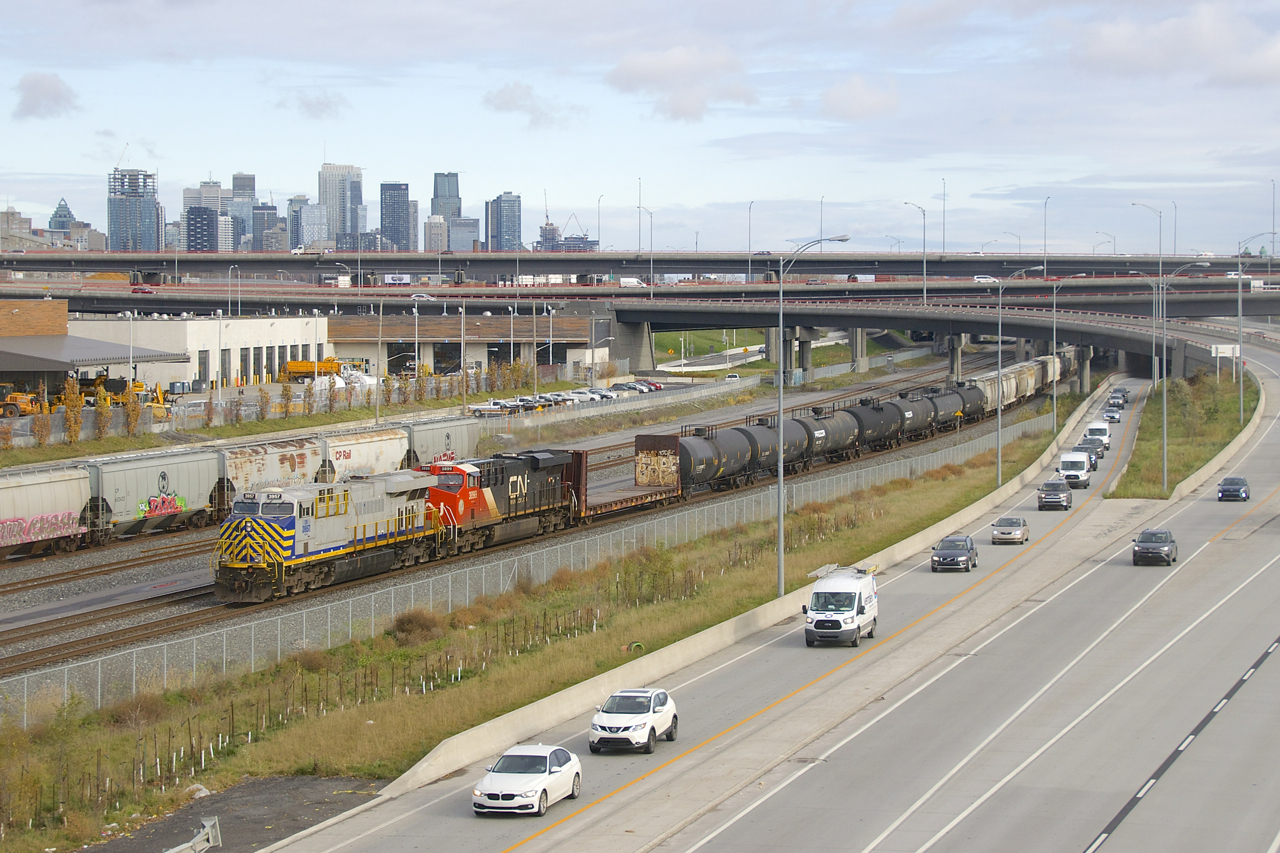 ES44AC's in two paint schemes (CN 3957 & CN 3899) lead CN 309 past the skyline of downtown Montreal.