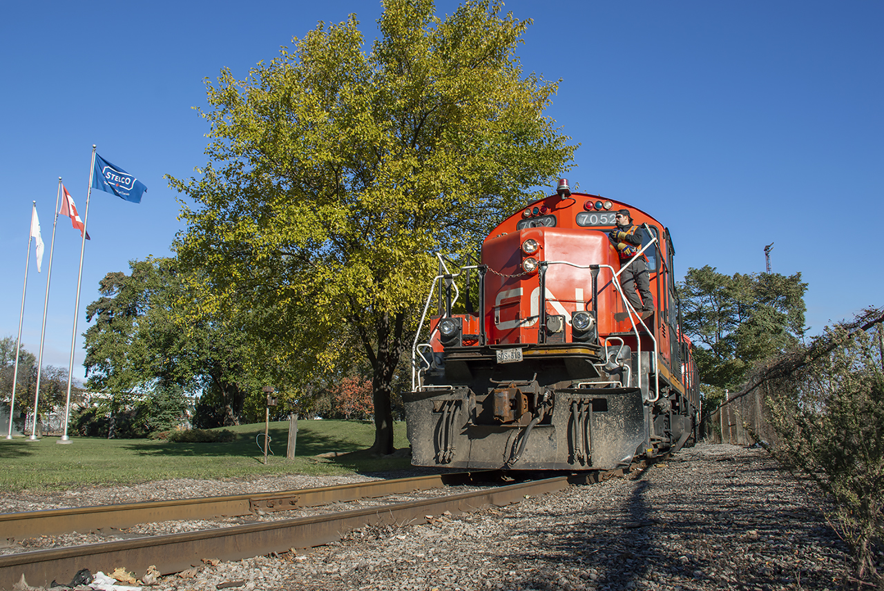 Keep It Beautiful.  A gorgeous sunny morning finds the 0700 job lifting a cut of coil cars out of the small yard for Railcare on the Irondale Lead, about to cross Burlington Street.  After lining the switch, they'll shove into Stelco to drop their train.

This isn't the only locomotive sporting a license plate in the area.