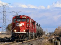 A large Canadian flag flaps in the crisp autumn morning wind as CP T14 stretches its legs over its more recently expanded territory. Over the past month the trains assignments have been expanded to now cover working the former "Expressway" yard in Hornby, now a bulk transfer facility operated by Cando. The train with its two matching GP20ECO's are slowly heading to the west end of the yard to drop a cut of tank cars before returning to the east end to lift another cut of cars before heading back to Streetsville. Lisgar GO station can be seen in the distance.