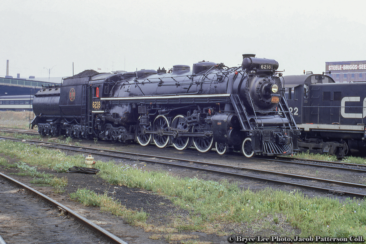 CNR 6218 is readied on the service tracks at Spadina roundhouse on the morning of September 20, 1970.  Note the fire hydrant and hose, likely used to fill the 11,600 gallon tender.  Today she will lead a UCRS fan trip from Union Station - Guelph - Caledonia - Hamilton and return.  Off to the right, one of the coach yard switchers, MLW S13 8522, idles away waiting to be called to duty.  Built in 1959 a the last of a 23 unit order, and the highest numbered of the 8500-series, it will be retired in 1990.At upper left the Spadina Avenue overpass spans the numerous tracks below.  At upper right, the top of the Steele-Briggs Seed Co. building can be seen at the corner of Spadina Ave and Front St.  The building was originally constructed in 1913 for Steele-Briggs Seed Company to centralize it's operations under one roof.   The company specialized in seeds for the Canadian climate and growing season, and shipped many of it's seeds out by rail, the sidings located on the south side of the building, lasting until removal from the parking lot in late 2015.*  *Information per the late (d. 2020) Toronto Historian, Doug Taylor.  Further information by clicking on Doug's name.Bryce Lee Photo, Jacob Patterson Collection Slide.
