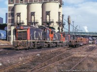 Sitting beneath the long-retired Spadina coal tower a line of GMD and MLW switchers are seen.  Note the hoppers at left to provide sand to the serving area towers, flatcars of wheel sets, and work service baggage cars.<br><br>At right one of the smokestacks of the Toronto Terminal Railways' Central Heating Plant (built in 1929, twin smokestacks <a href=http://www.trha.ca/uploaded_images/left1929-731913.jpg>seen here</a>), which supplied heat to Union Station, the Royal York Hotel, CNR and CPR express buildings, CPR John Street Roundhouse, and a number of other office buildings.  Originally burning coal, the plant was eventually converted to natural gas, and finally shutdown in the 1980s once the TTR converted to a commercial supplier, and demolished in 1990.<br><br>SW1200RS 1241, built in 1956, renumbered 7300 in 1985, to <a href=http://www.railpictures.ca/?attachment_id=19241>CN Sweep 7100</a> in 1986.  MLW S4 8033, built 1954, retired in the early 80s.  SW1200Rs 1254, built 1956, retired 1993 and sold to Zyndar Bothers in Vaughan (then switching contractor at Vaughn Intermodal Terminal), renamed Plusar Inc., and <a href=http://www.trainweb.org/oldtimetrains/industrial/ont/Plusar1254.jpg>finally Parsec Intermodal of Canada Ltd. 1254.</a>  Disposition unknown.  MLW S13 8514, built 1959, rebuilt as S13u 8706 in the late '80s, retired circa 1996-97, sold to Canac, disposition unknown.<br><br>More Spadina Coal Tower:<br>Bill Thomson: 6167 being readied for an excursion; <a href=http://www.railpictures.ca/?attachment_id=28955>April 1963.</a><br>VIA units by Pierre Fournier, <a href=http://www.railpictures.ca/?attachment_id=1818>April 1985.</a><br><br><i>Paul Martin Photo, Jacob Patterson Collection Slide.</i>