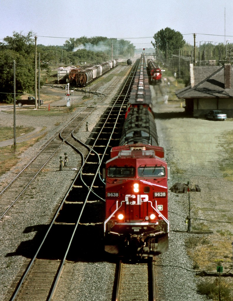 Westbound grain empties pass the 1893 built station while the wayfreight sits in the siding. CN Main and station sits 1/2 block to the right