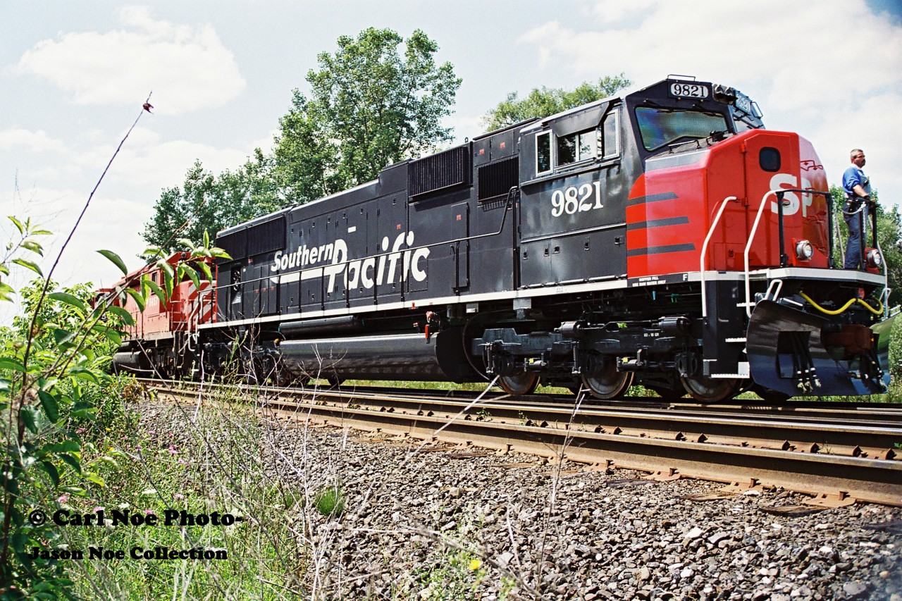 Southern Pacific SD70M 9821 gets its first baby pictures taken as it is lifted at the GMDD facility in London, Ontario by a CP westbound powered by SD40-2’s 5841 and 5657.