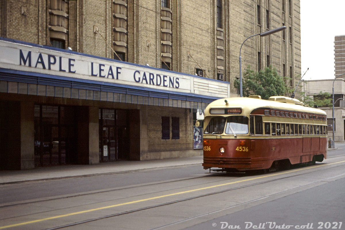 Operating on a May 24th 1987 fantrip around town, chartered TTC PCC 4536 (an A8-class car built in 1951) poses in front of Toronto's downtown hockey shrine: Maple Leaf Gardens. At this time in the 80's, the remaining PCC fleet was on its way out (some like 4536 acquired large inelegant front numbers in their last years) but the TTC was in the early stages of a rebuild program for a handful of their A8 cars, the newest PCC cars in the fleet, for their future downtown Harbourfront route. 4536 would be one of the lucky cars rebuilt, emerging as 4607 in 1990 before the program was cancelled after 19 cars due to new vehicle accessibility requirements. The rebuilt PCC's mainly operated on the 604 Harbourfront route until they were retired and dispersed to other agencies, museums and owners in the mid-90's (4607 was sent to Phoenix AZ).

Streetcars have trundled along Carlton Street past Maple Leaf Gardens for decades, hauling hockey fans and other event-goers to the Gardens from 1931 until the venue officially closed in 1999 and the Toronto Maple Leafs moved to the new Air Canada Centre. The building was mothballed after, but in the late 2000's a joint partnership between Ryerson University and Loblaws was formed to renovate the area into a ground-floor Loblaws grocery store, and Ryerson's Mattamy Athletic Centre (featuring a hockey rink) built above it.

Original photographer unknown, Dan Dell'Unto collection slide.