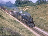 A westbound freight behind heavy Mikado 5417 with Pacific 2235 on the point as a helper approaches the <a href=http://www.railpictures.ca/?attachment_id=12679>wooden bridge just east of Galt.</a>  The helper will stay on until cresting the grade at Orr's Lake, where it will duck in the siding, coast back down to Galt, head around the wye, and run light back to Toronto.  Note the brakeman hanging out the door.  There was once two farm bridges at this location, both of which can be seen in <a href=https://lib.uwaterloo.ca/locations/umd/project/IMC17.html>this 1945 aerial.</a><br><br><i>Original Photographer Unknown, Jacob Patterson Collection Slide.</i>