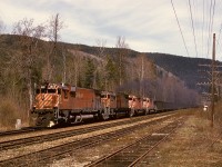 Providing a hint of the future, with two MLW M-630s (4566+4561) leading but two GMD SD40-2s (5613+5616) trailing them (and another two SD40-2s plus a Robot car, 5579+5644+1015, unseen mid-train), this westward train of coal is passing milepost 28 at Craigellachie (about 0.15 mile east of the cairn) at 1205 on Tuesday 1974-04-23.

<p>Note the telegraph pole crossarm arrangement of two long plus one shorter plus one long, in my experience unique to the CP Shuswap sub., and first noticed years earlier as a bored kid while eastward by highway from Kamloops.